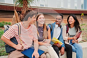 Group of multiracial young academic students talking together sitting at university campus. Classmates having a friendly