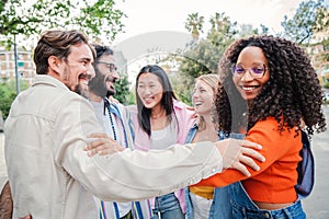 Group of multiracial young adult people bonding and embracing closeness on circle together. On foreground an african