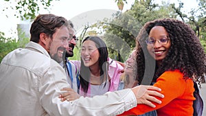 Group of multiracial young adult people bonding and embracing closeness on circle together. On foreground an african