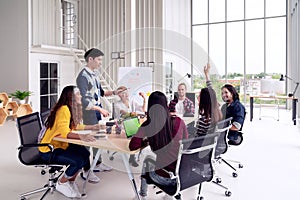 Group of multiracial young creative team talking, laughing and brainstorming in meeting at modern office concept. Female standing