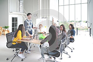 Group of multiracial young creative team talking, laughing and brainstorming in meeting at modern office concept. Man standing and