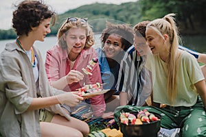 Group of multiracial young friends camping in campsite near lake and having barbecue together.