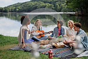 Group of multiracial young friends camping near lake and and having barbecue together.