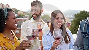 Group of multiracial young friends hanging out while having party at rooftop