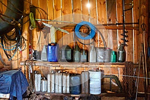 A group of old canisters and cylinders stand on shelves in a wooden shed