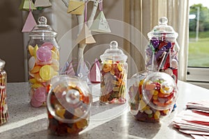 A group of old fashioned glass jars of delicious sweets, with party decorations in the background