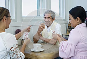 group of old pensioners playing cards at home