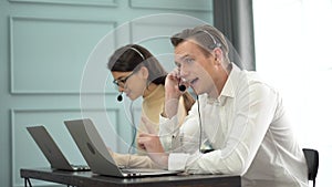 group of operator man and woman working with headset and laptop computer in a call centre . customer service help desk online .