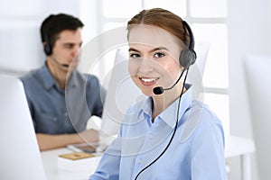Group of operators at work. Call center. Focus on beautiful woman receptionist in headset at customer service. Business