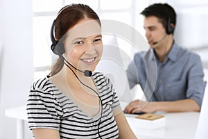 Group of operators at work. Call center. Focus on beautiful woman receptionist in headset at customer service. Business