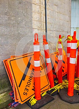 Group of orange road works stanchions and signs stored away.