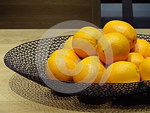 Group of oranges in round tray on wooden table