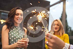 Group of partying girls with flutes with sparkling wine and bengal fire