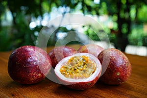 Group of passion fruit with half cut on wooden table with blur green garden background, copy space, healthy food concept