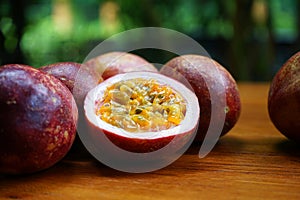 Group of passion fruit with half cut on wooden table with blur green garden background, copy space, healthy food concept