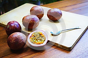 Group of passion fruit with half cut on wooden table with blur green garden background, copy space, healthy food concept