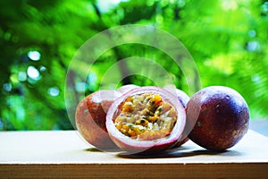 Group of passion fruit with half cut on wooden table with blur green garden background, copy space, healthy food concept