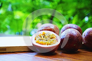 Group of passion fruit with half cut on wooden table with blur green garden background, copy space, healthy food concept