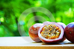 Group of passion fruit with half cut on wooden table with blur green garden background, copy space, healthy food concept