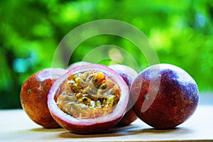 Group of passion fruit with half cut on wooden table with blur green garden background, copy space, healthy food concept