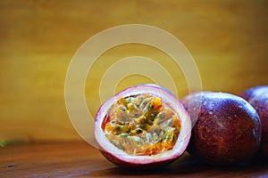 Group of passion fruit with half cut on wooden table with blur green garden background, copy space, healthy food concept