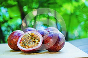 Group of passion fruit with half cut on wooden table with blur green garden background, copy space, healthy food concept