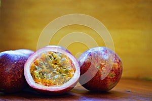 Group of passion fruit with half cut on wooden table with blur green garden background, copy space, healthy food concept