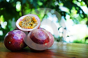 Group of passion fruit with half cut on wooden table with blur green garden background, copy space, healthy food concept