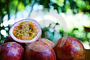 Group of passion fruit with half cut on wooden table with blur green garden background, copy space, healthy food concept