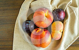 Group of peaches and plums on a beige napkin