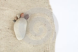 Group of pebble stones on sand creating de form of a foot in iso