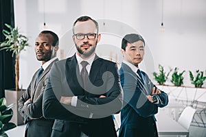 group of pensive multiethic businessmen with folded arms looking