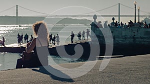 Group of people admiring the stunning sunset from the end of a pier on the Tagus River in Lisbon