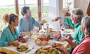 Group of people of all ages eating together at home food - happy adults and seniors togetherness - have lunch indoors