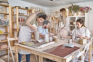 Group of people in aprons making ceramic crafts together in a workshop.