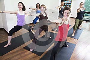 Group of people with arms outstretched doing yoga during a yoga class photo