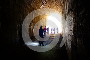 Group of People Biking Through Tunnel with Headlights Hiawatha Trail