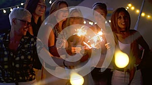 Group of people celebrate together the nightlife - romantic sparklers for party event like Christmas or new year eve - together in