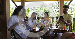 Group Of People With Cell Smart Phones Messaging Sititng at Table On Summer Terrace, Mix Race Men And Women Holding