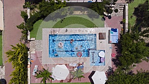 Group of people with children playing and having fun in the swimming pool aerial view
