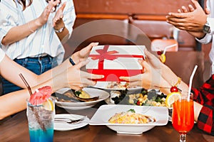 Group of people clapping hands to congratulate each other for birthday gift or rewards during dinner.