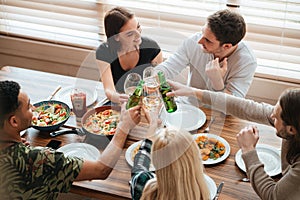 Group of people clinking glasses and bottles at the table