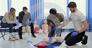 Group of people CPR First Aid Training course. CPR teen dummy first aid training.