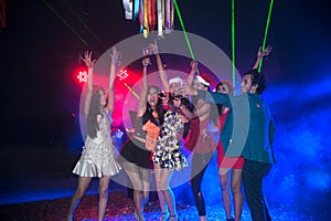 Group of people dancing at night club party and lights background.