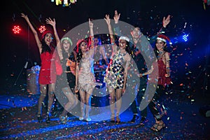 Group of people dancing at night club party and lights background.