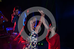 Group of people dancing at night club party and lights background.