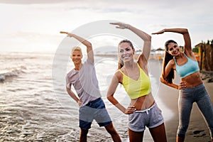 Group of people doing exercises on the beach. Fitness, training, sport and people concept