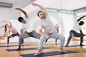 Group of people doing stretching exercises in fitness studio
