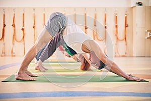 Group of people doing yoga downward facing dog pose on mats at studio