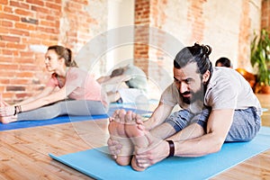 Group of people doing yoga forward bend at studio